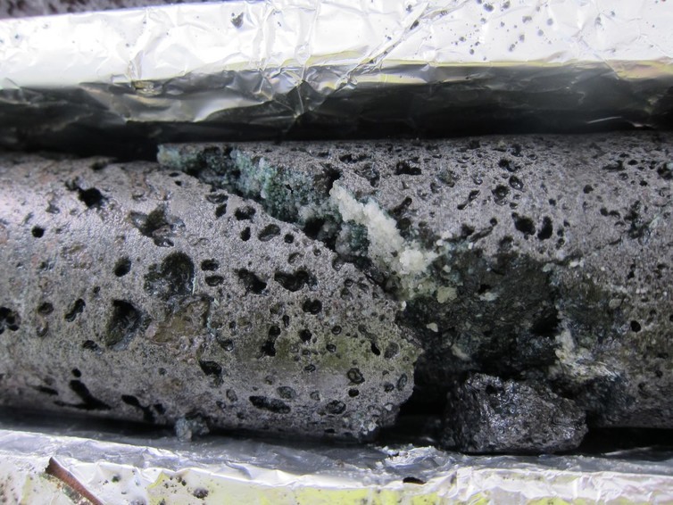 The fracture in this basalt rock shows the white calcium carbonate crystals that form from the injection of CO2 with water at the test site. (Photo: Annette K. Mortensen)